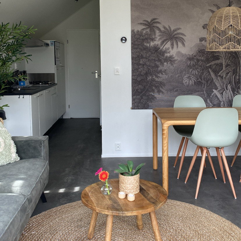 Woonkamer en eethoek met lichte stoelen naast de open keuken.